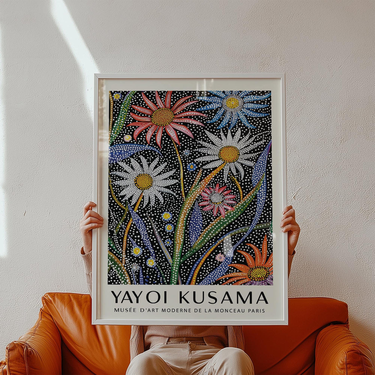Abstract Botanical wall art with dotted flowers and colourful leaves held above an orange leather chair