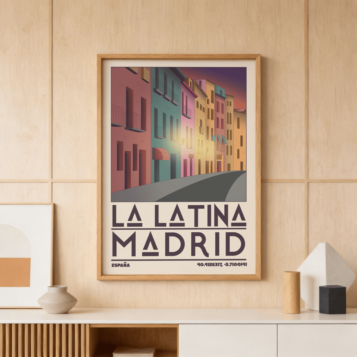 Framed Madrid City wall art of colourful buildings at sunset on a wood panel wall above a shelf with a vase