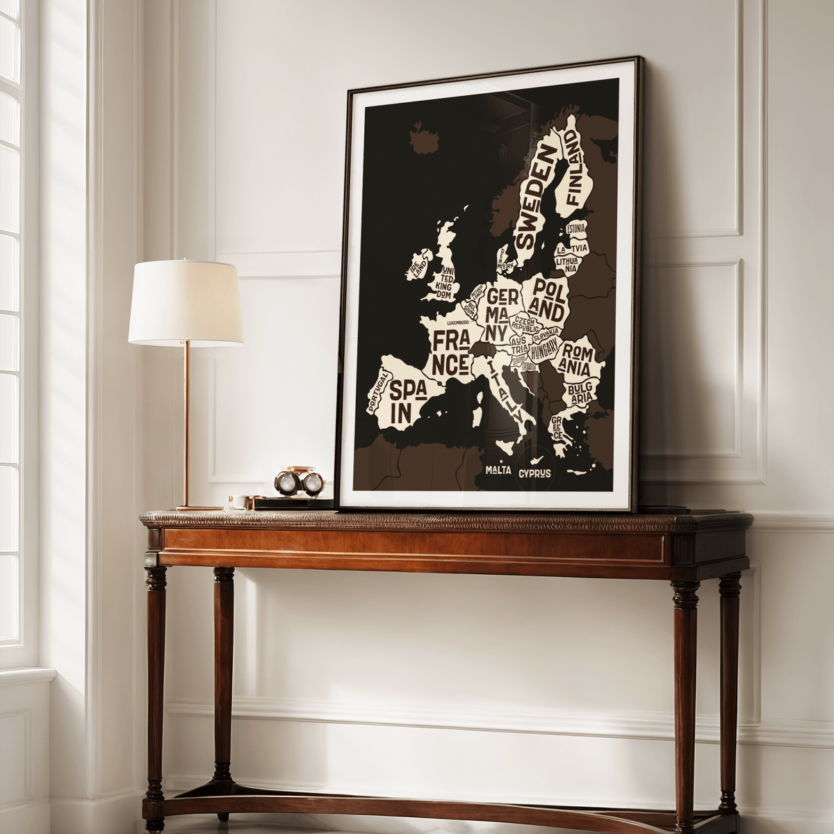 Europe Poster leaning on a wooden table next to a white lamp in a cream room
