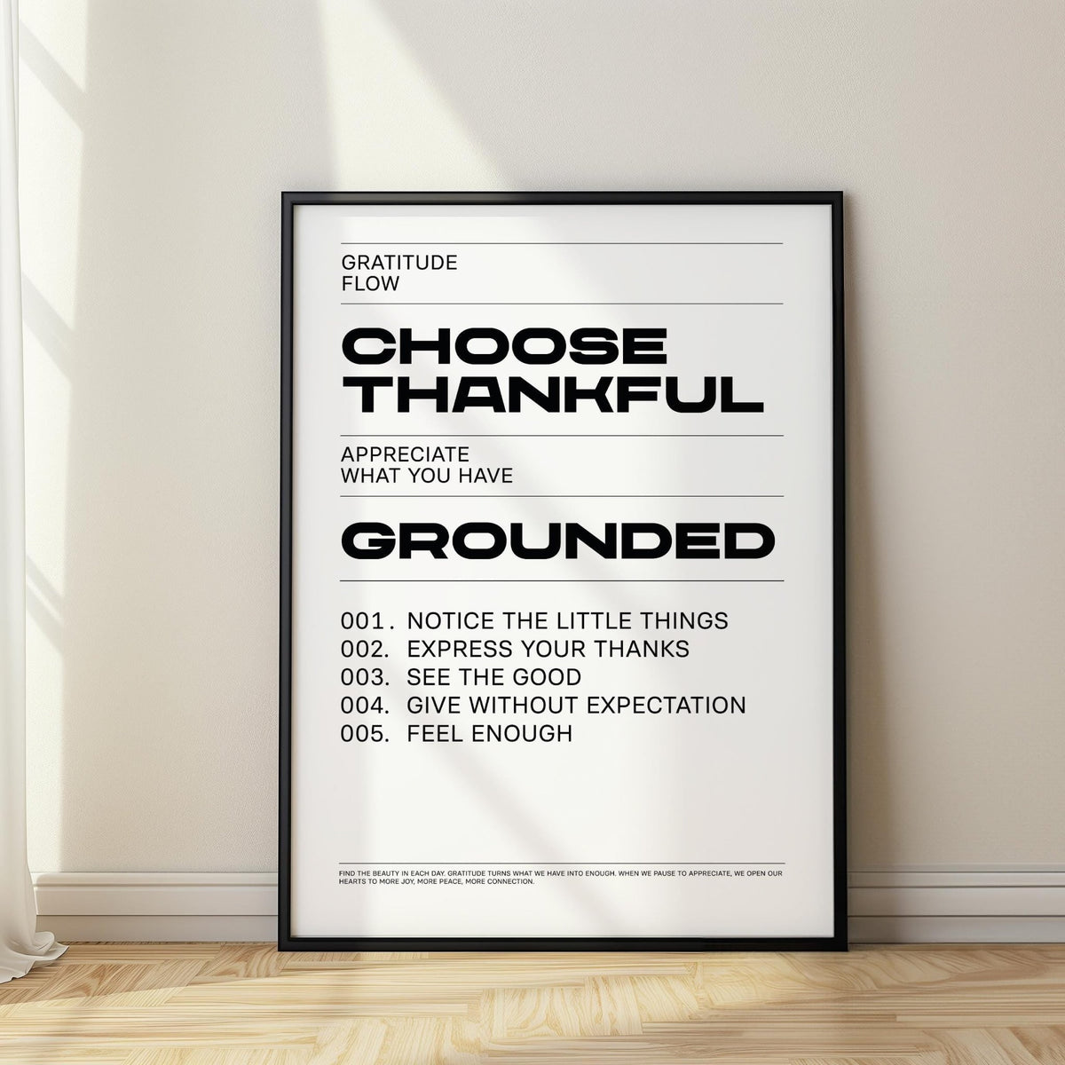 Gratitude wall art leaning on a wooden floor with black frame and minimalist black text