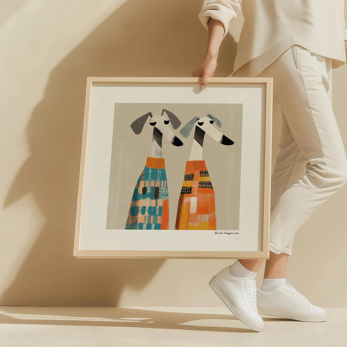 Framed wall art dog illustration of two greyhounds in colourful patterned jumpers held by a person
