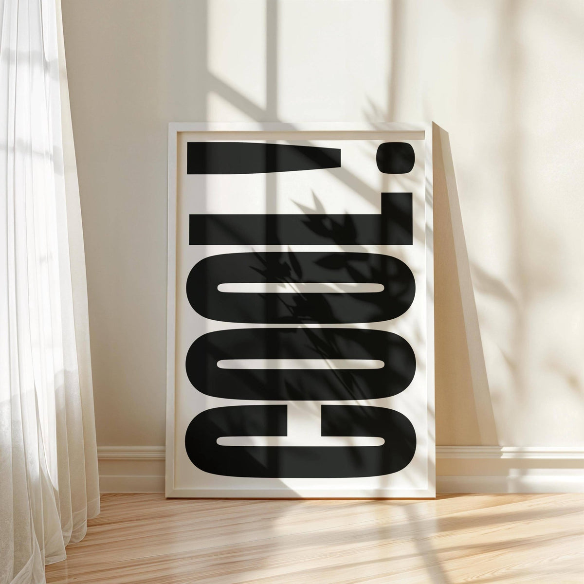 Print leaning on floor with cool typography in black and white with shadows from plant and window