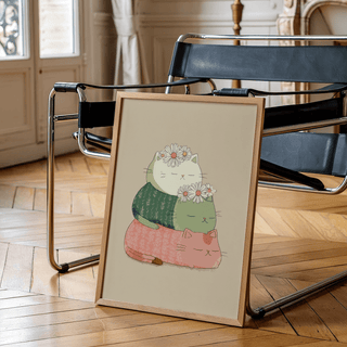 Cute Cat Art Print leaning on a chair with tan wooden frame and stacked cats with daisies