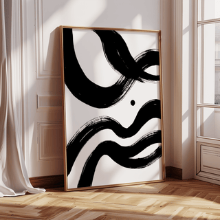 Print leaning on a floor featuring black and white abstract ink waves with wooden floor visible