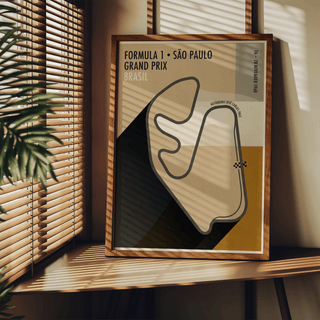 Framed Sao Paulo Race Circuit Diagram Poster with beige and black tones on a wooden table with a plant nearby