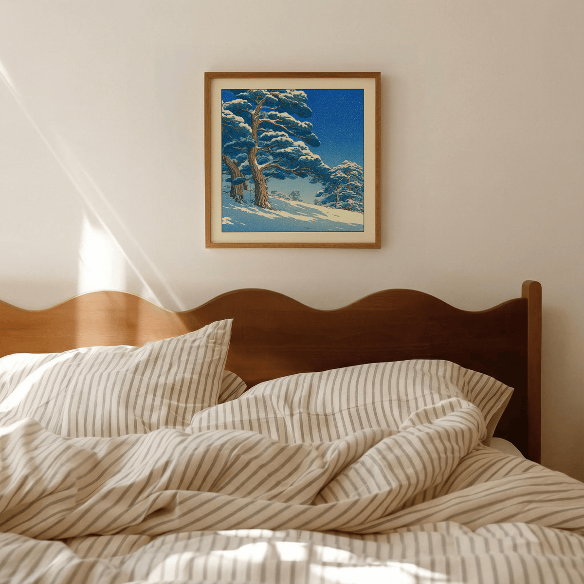 Hasui Kawase Snowy Pines Art Print hanging above a wooden bed with striped bedding in a warmly lit room