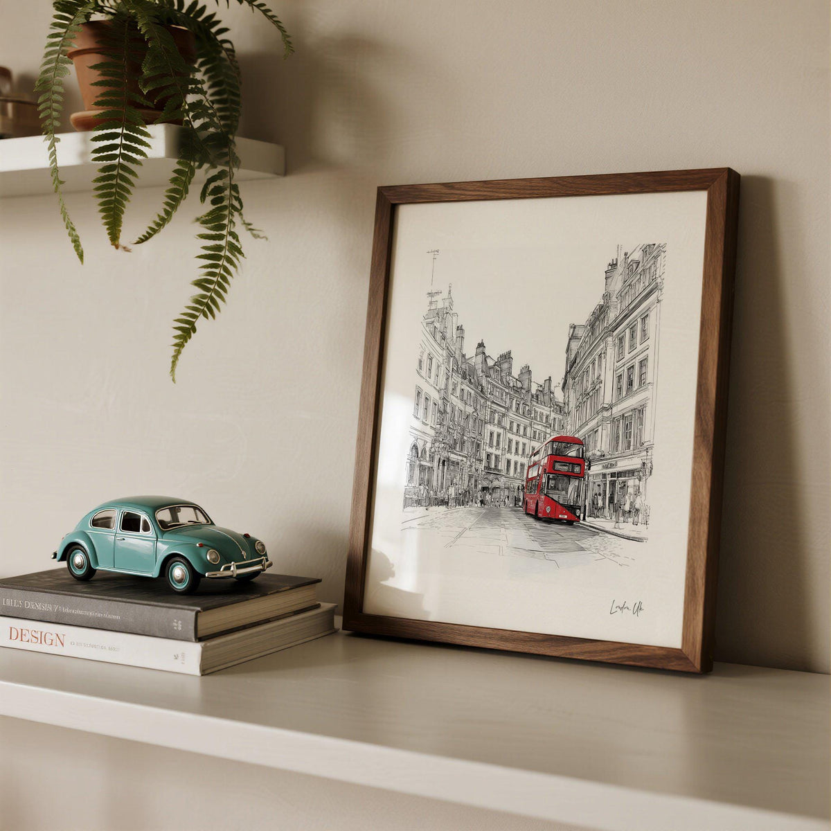 Framed London England wall art of a red double-decker bus with sketchy black buildings and a model car nearby