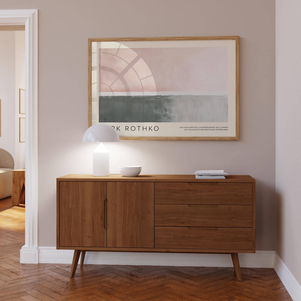 Horizontal wall decor of abstract blocks in muted pink and grey above a wooden sideboard with lamp and bowl