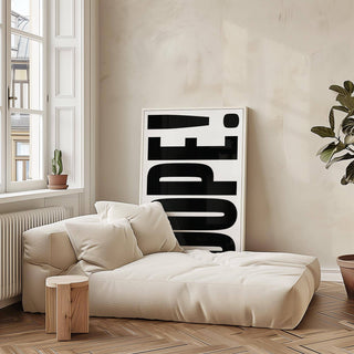 Print leaning on the floor with dope typography in black and white beside a beige sofa with cushions