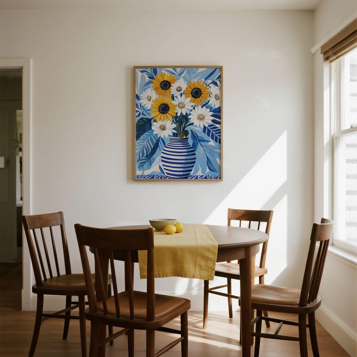 Art of Sunflowers framed print of yellow sunflowers and white daisies in a blue striped vase above a dining table