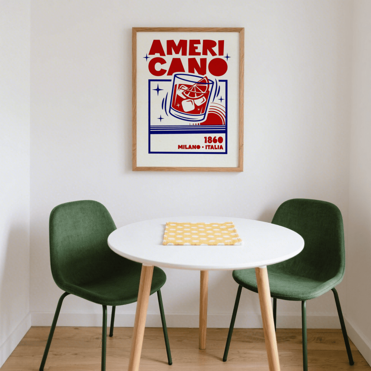 Americano Cocktail Poster above a round white table with two green chairs in a bright corner