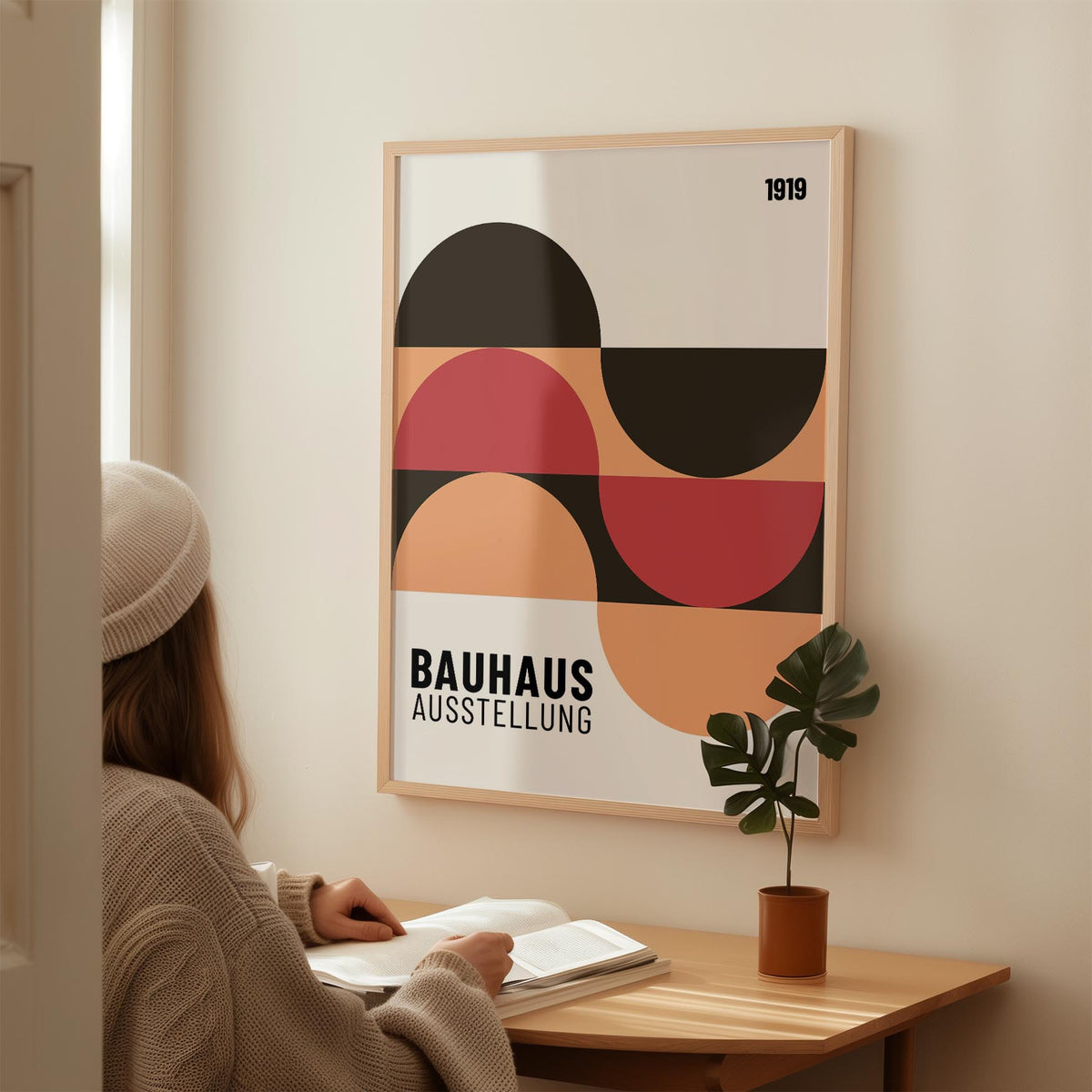Home Office wall art with abstract geometric shapes in red black and beige above a desk with a potted plant