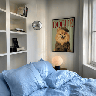 Pomeranian wall art of a dog in soldier uniform with red text in a bedroom above a bedside lamp