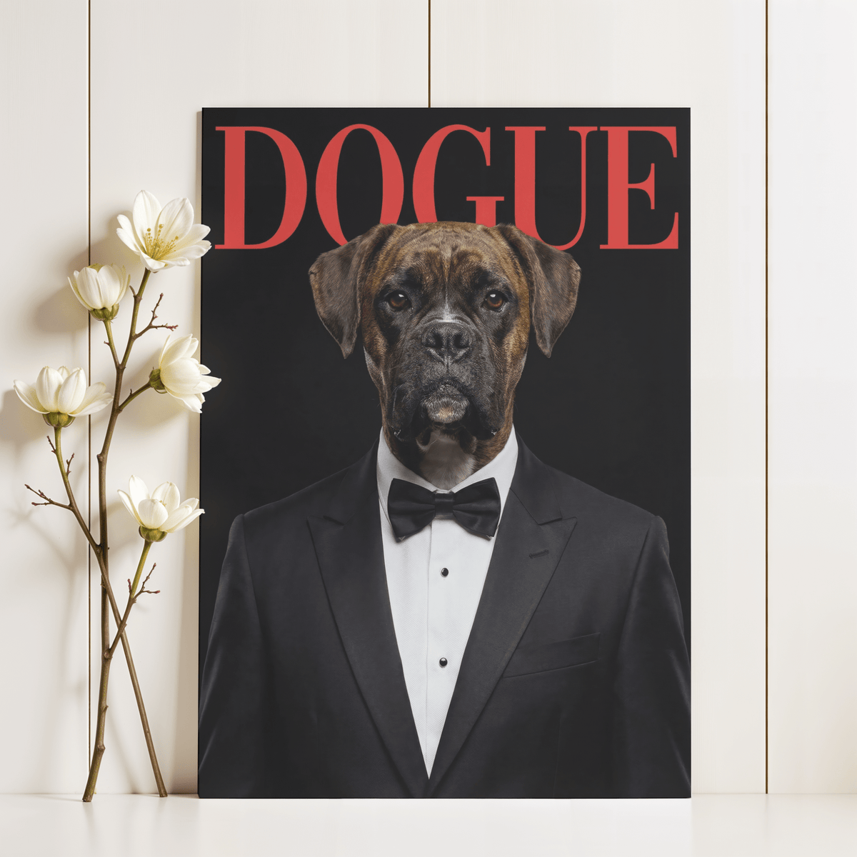Dogue Poster leaning on shelf featuring a boxer dog in tuxedo with red text and black background next to white flowers