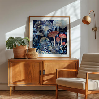 Print leaning on a wooden sideboard with toadstools in blue and red beside a potted plant and wall lamp