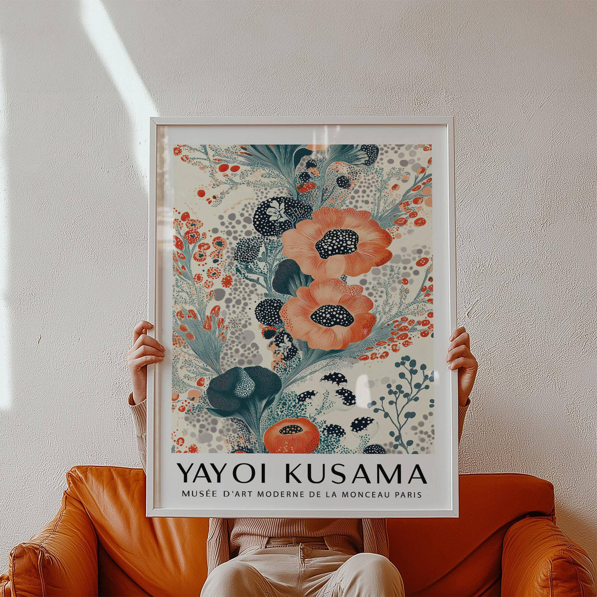 Framed floral poster wall art with stylised orange and dark blue blooms held above an orange leather armchair