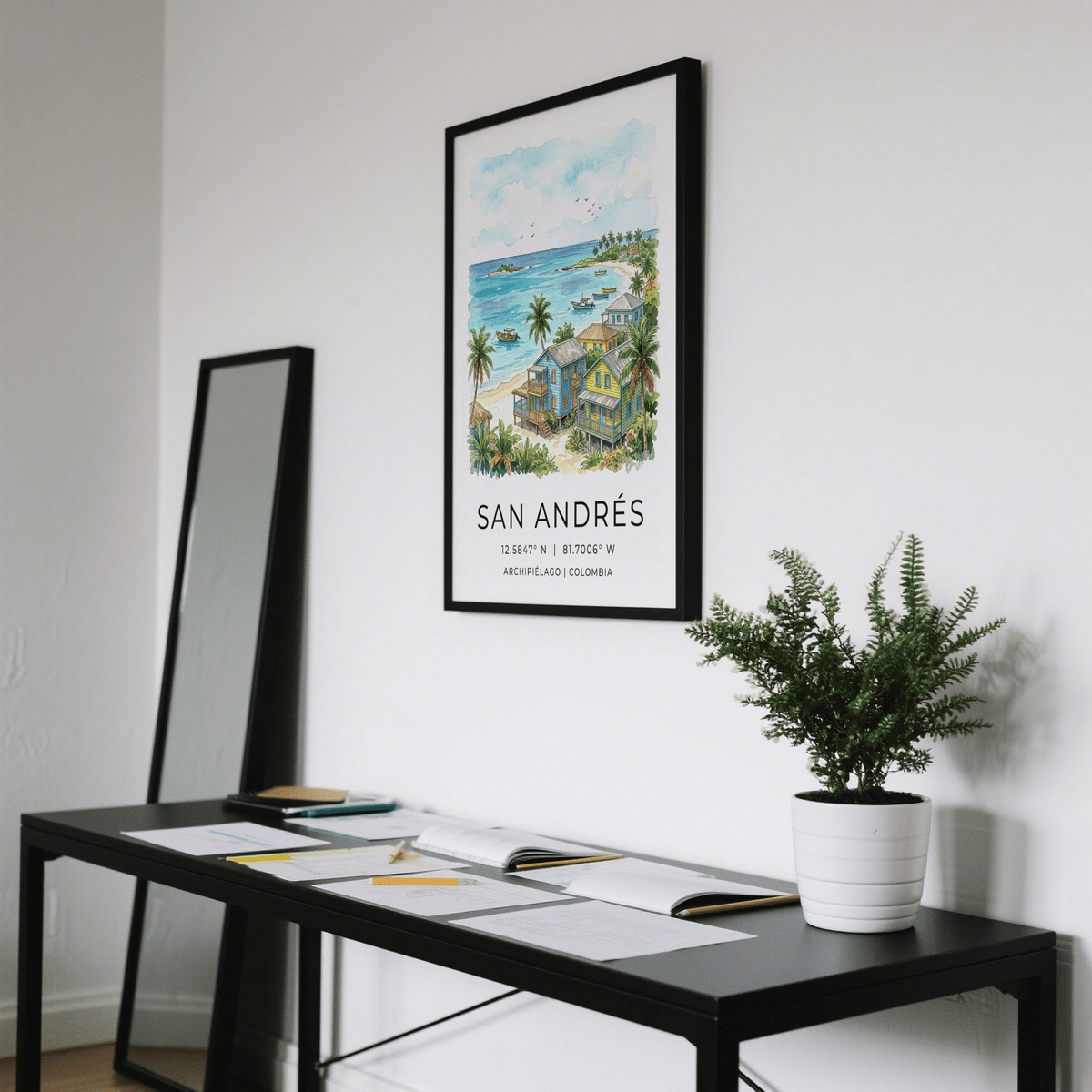 San Andres Art Print hanging above a black desk with a white pot plant in a white room