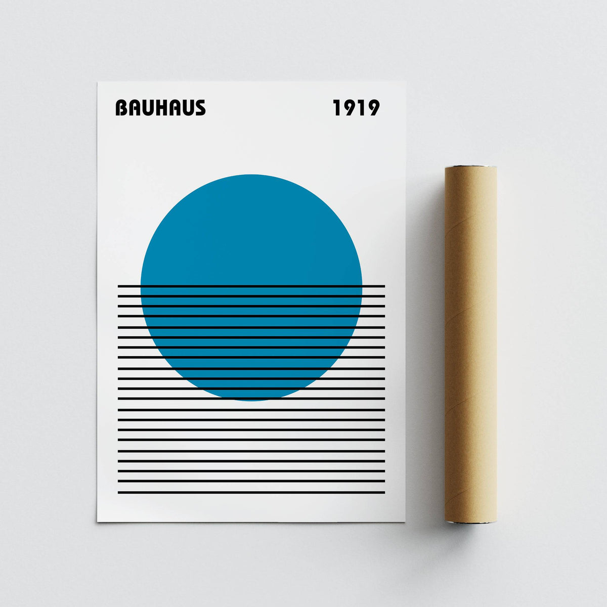 Minimalist Art print with blue circle and black horizontal lines leaning on a grey surface beside a brown packaging tube
