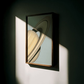 Framed Saturn wall art illuminated by angled sunlight casting shadows