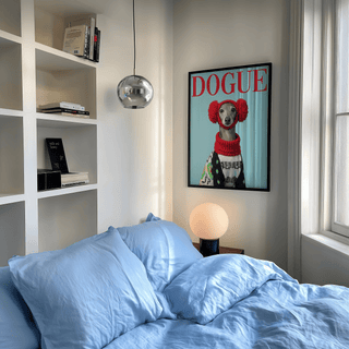 Italian Greyhound Wall Art of a dog in red earmuffs above a wooden bedside table lamp in a bedroom