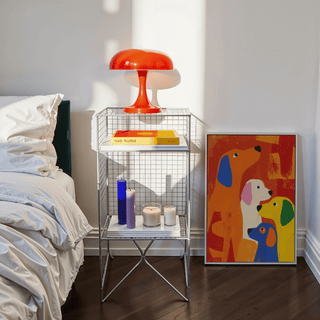 Print of colourful abstract dogs leaning on the floor next to a metal shelf with a red lamp and candles