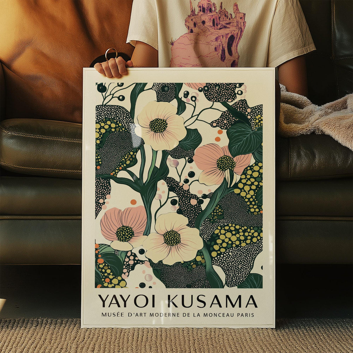 Framed Green Pink Wall Art with poppy flowers held in hands against a dark leather sofa