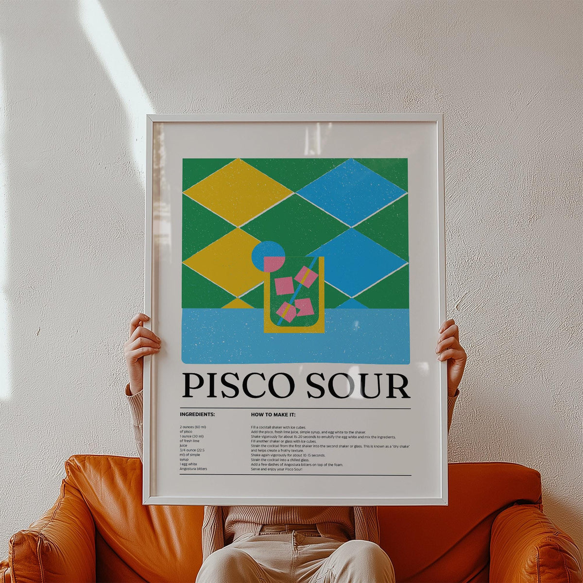 Colorful Posters artwork of a pisco sour cocktail illustration with yellow and blue shapes held by a person above an orange leather sofa