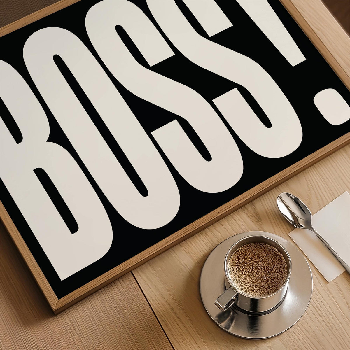 Close-up of Boss typography print in black and white with coffee cup on wooden table