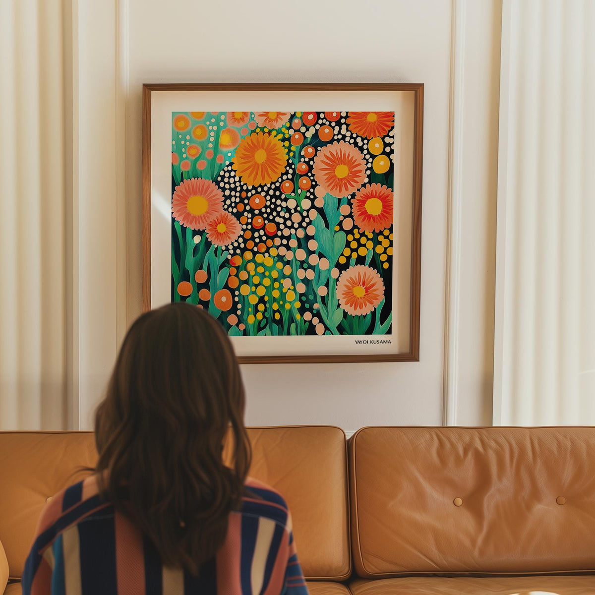 Colorful Flower Art framed print with bright abstract flowers in orange and yellow above a tan leather sofa