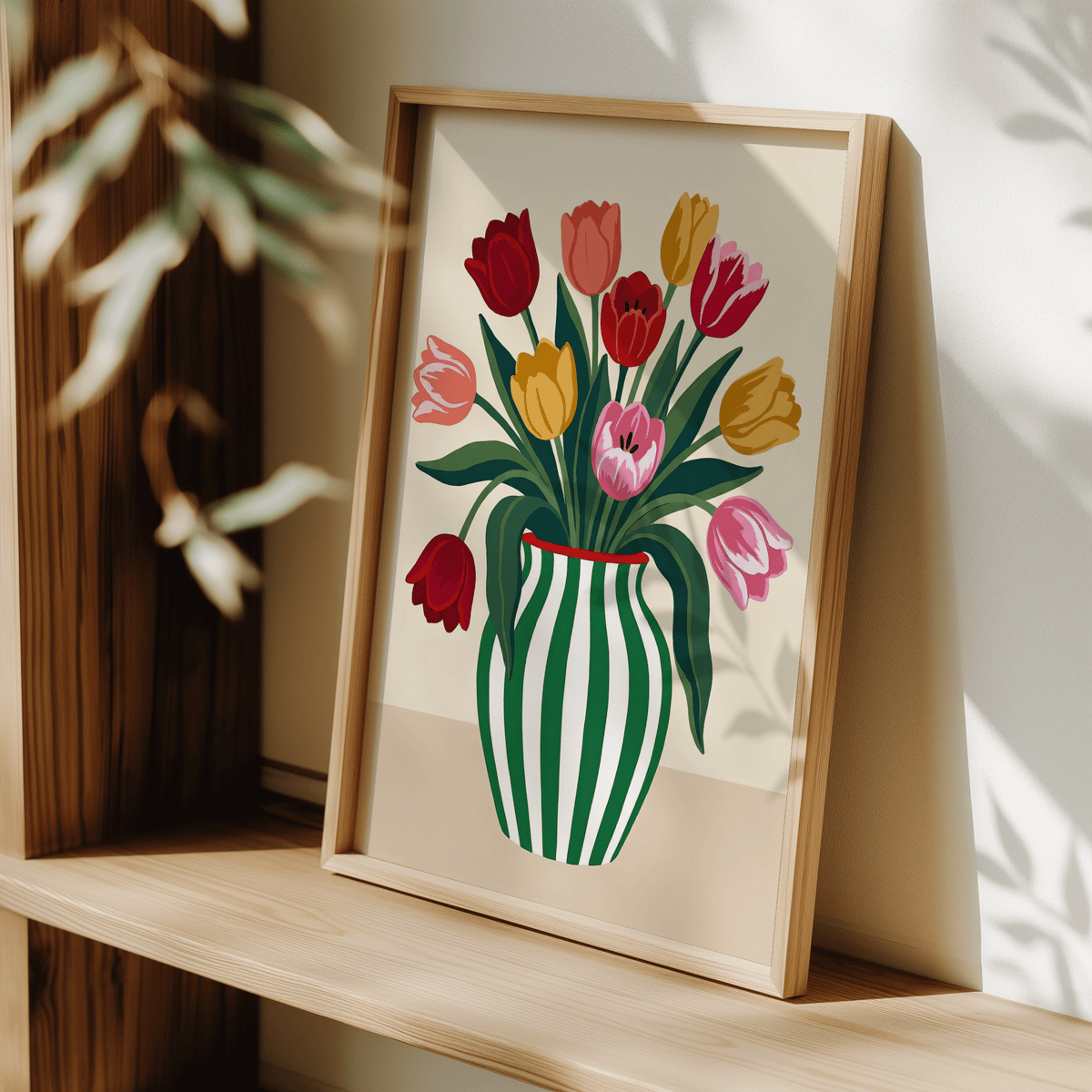 Print leaning on a shelf of multicolour tulips in a green and white striped vase with natural light and foliage shadows