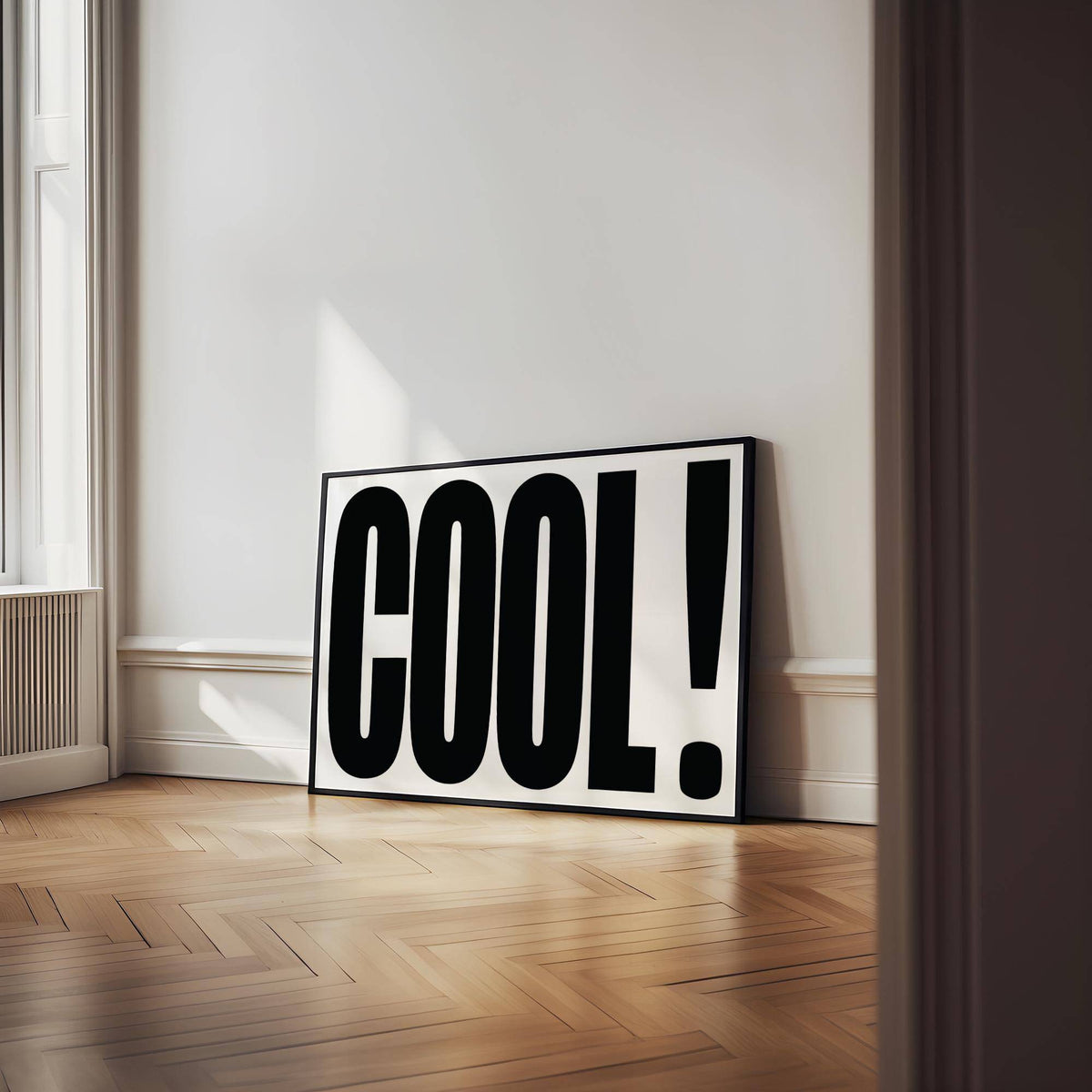 Cool Typography Poster leaning on a wooden herringbone floor against a white wall with natural light