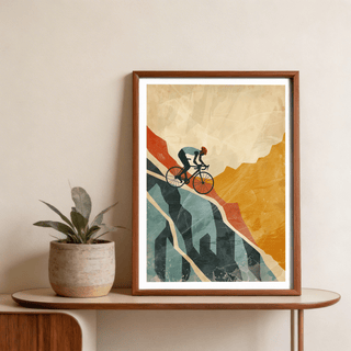 Framed mountain biking art print with orange and blue abstract cyclist leaning on a wooden table near a plant