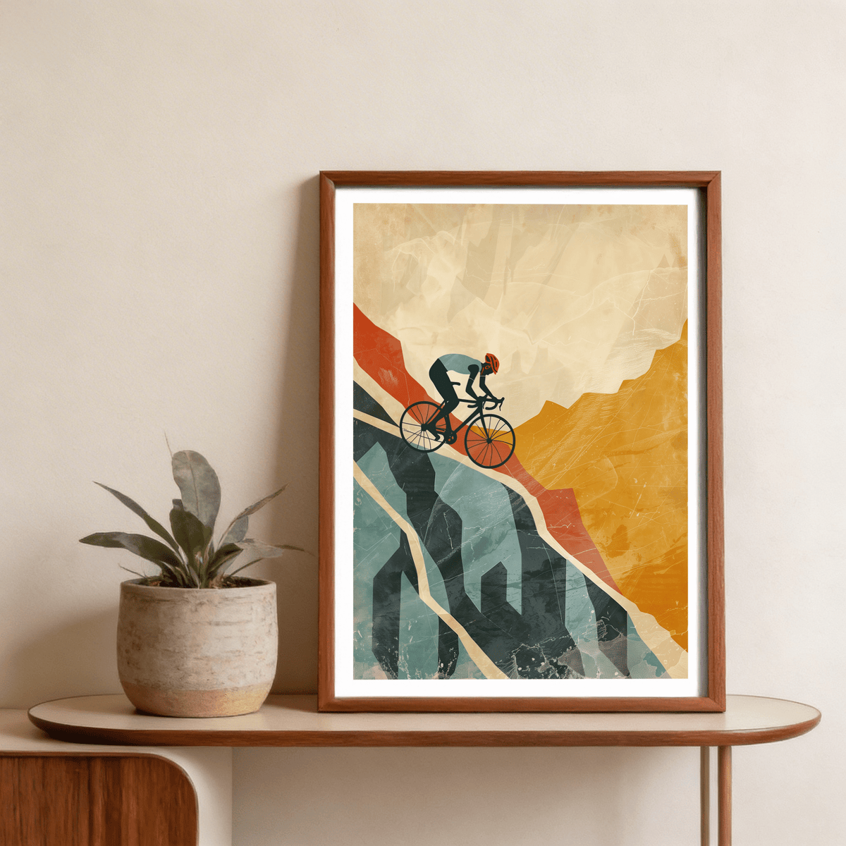Framed mountain biking art print with orange and blue abstract cyclist leaning on a wooden table near a plant