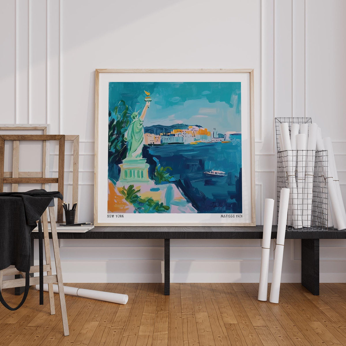 Holiday Posters leaning print of the Statue of Liberty in blue and green on a black bench with rolled papers nearby