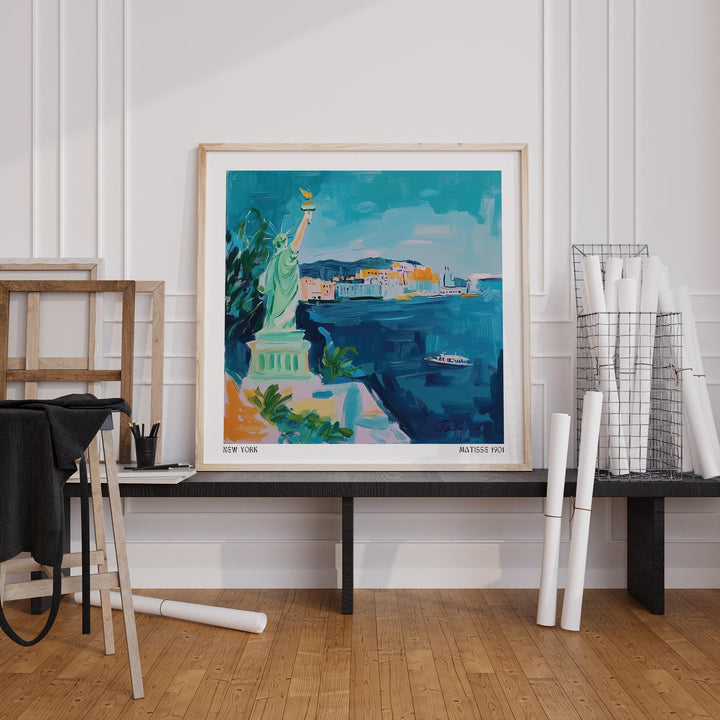 Holiday Posters leaning print of the Statue of Liberty in blue and green on a black bench with rolled papers nearby