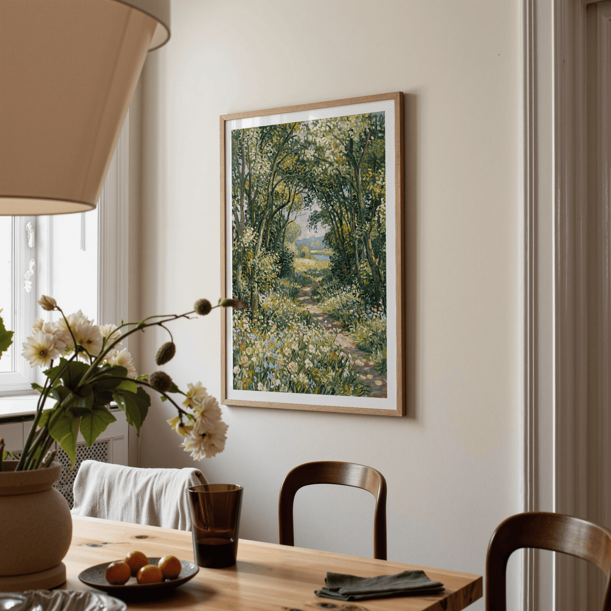 Impressionist art print of a woodland path with green and yellow tones hanging above a dining table