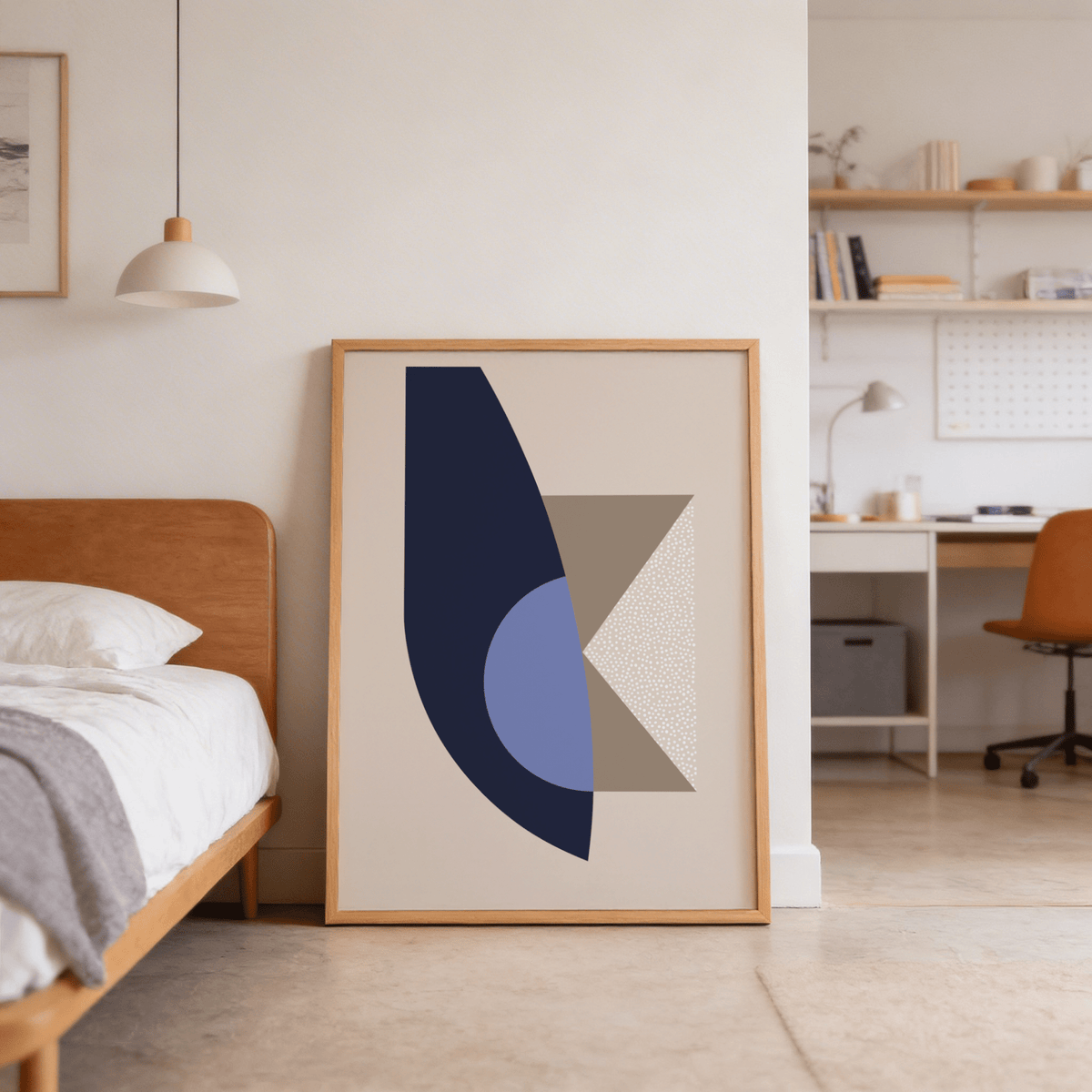 Modern wall art print leaning against a wall featuring abstract geometric shapes in blue and beige in a bedroom