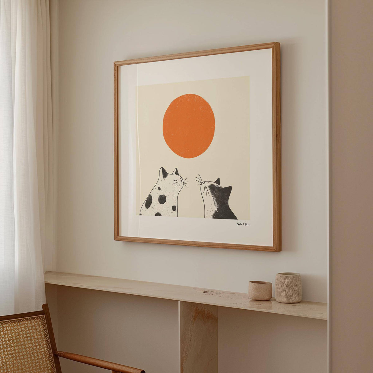 Orange Cat Art print of black and white cats with large orange sun on wall above light wooden shelf