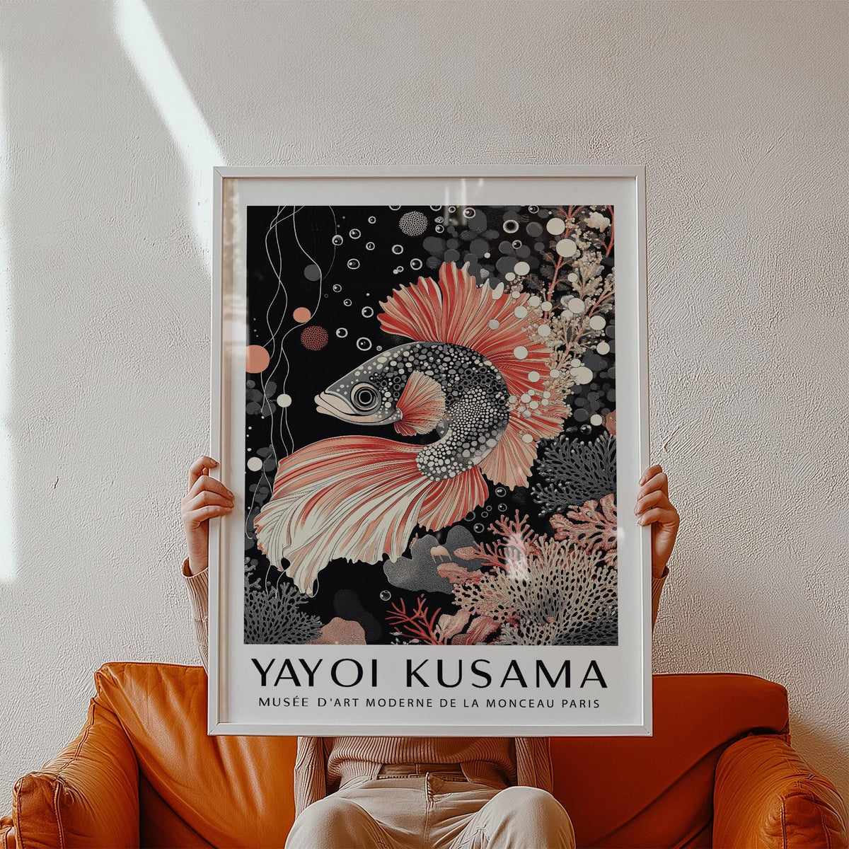 Asian wall art of a detailed koi fish illustration with coral tones and a black background held in front of a wall above a brown leather