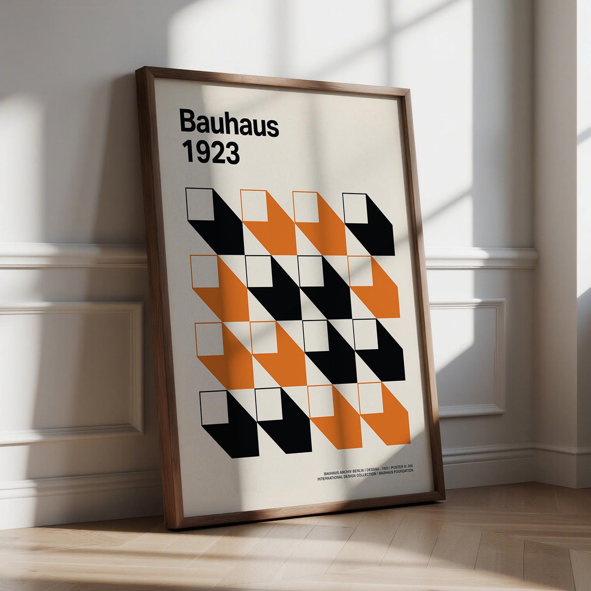 Print leaning on the floor with orange and black geometric grid artwork in brown frame