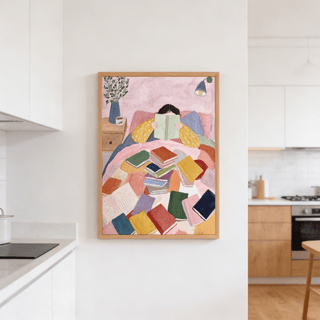 Woman Reading In Bed art print with colourful books and a plant on a bedside table in a kitchen