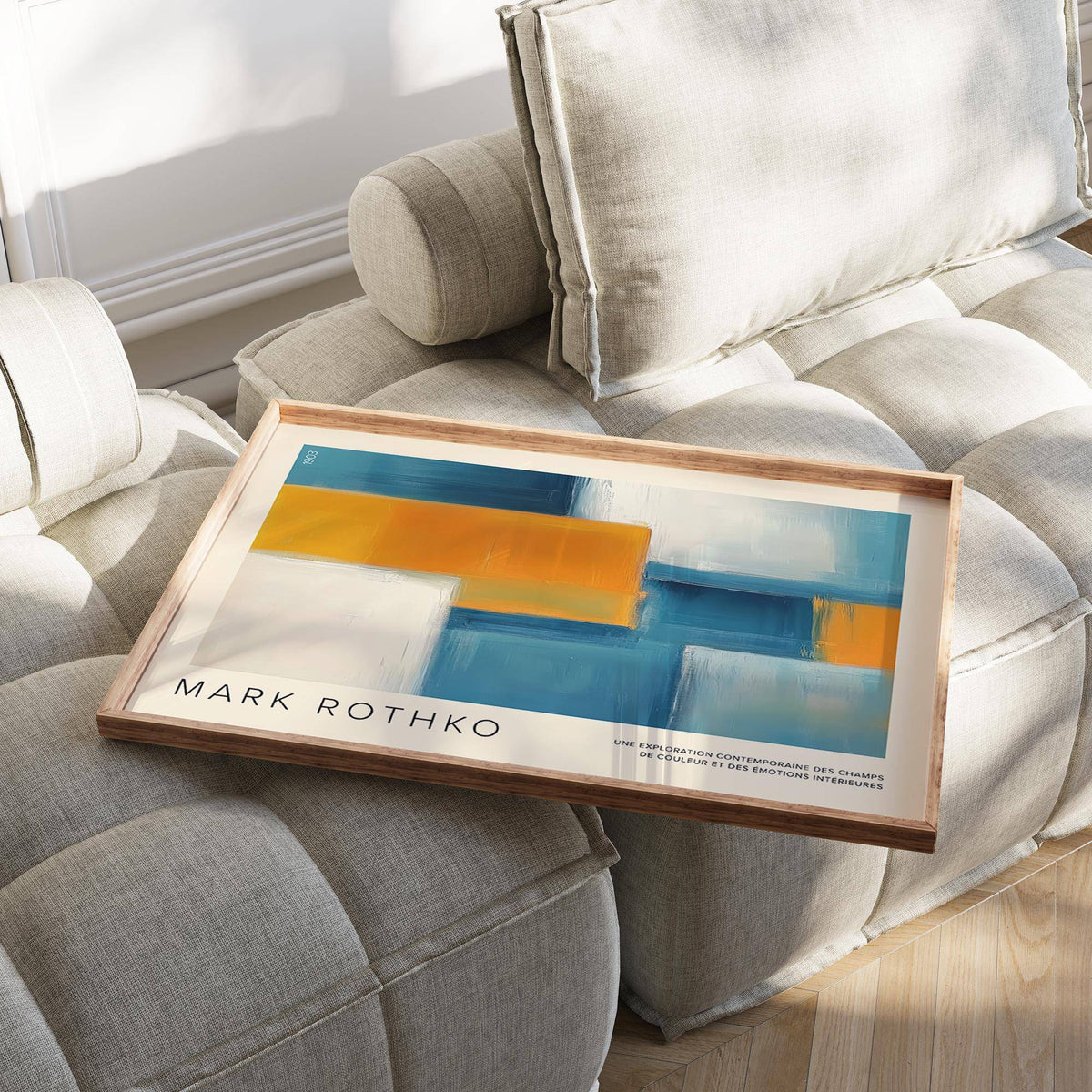 Wide Wall Art with abstract geometric blocks in blue and orange lying on a beige cushioned chair