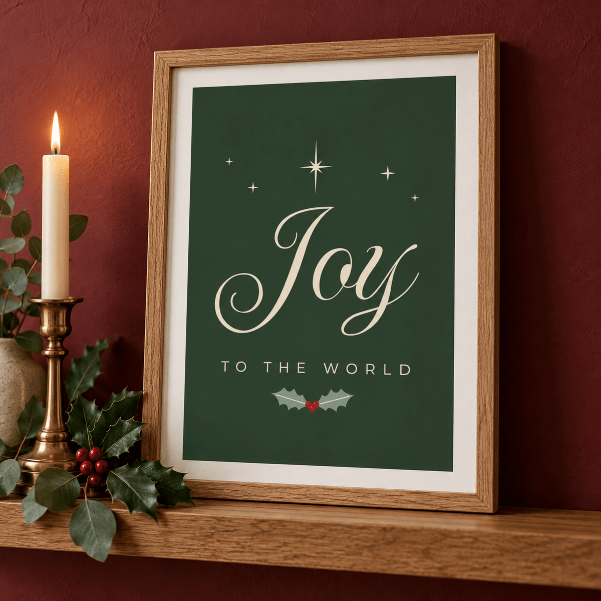Close view of the Joy print with a brass candlestick and holly on a red wall