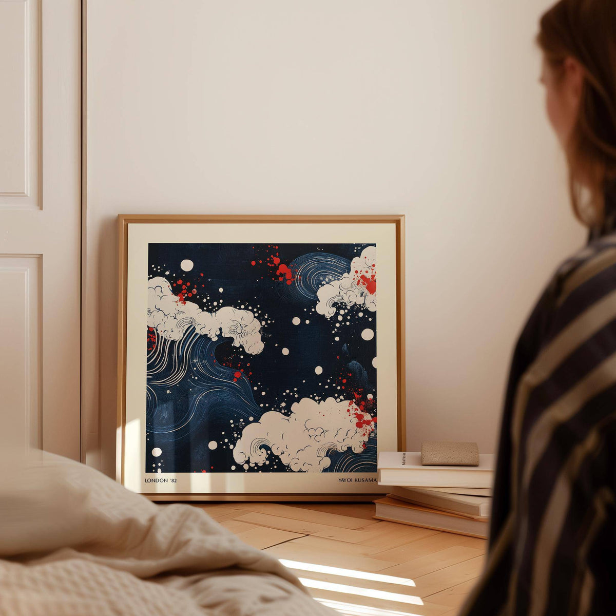 Print leaning on a floor showing abstract Japanese art stylized waves in navy blue white and red near a stack of books