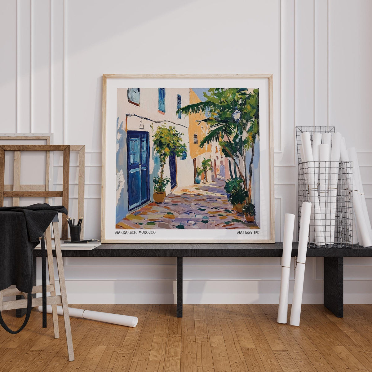 Morocco wall art of a Mediterranean street scene in blues and greens leaning on a black table in a light room