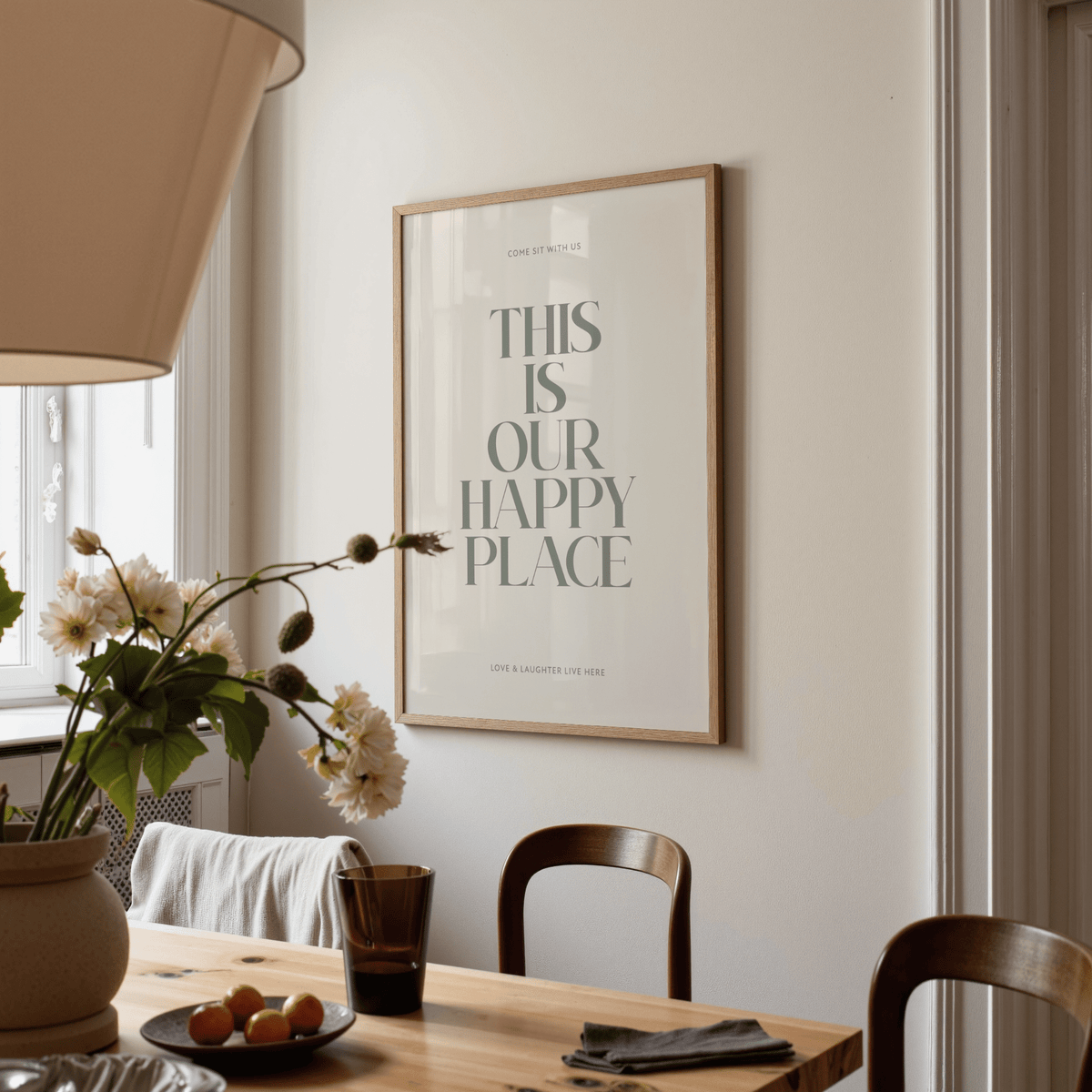 Inspirational wall sign with minimalist quote in grey on cream wall above dining table with flowers