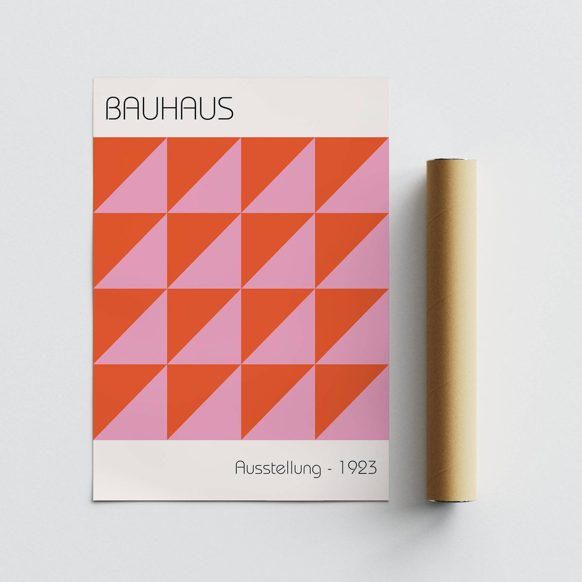 Modern wall art flat laid with red and pink geometric triangles beside a packaging tube