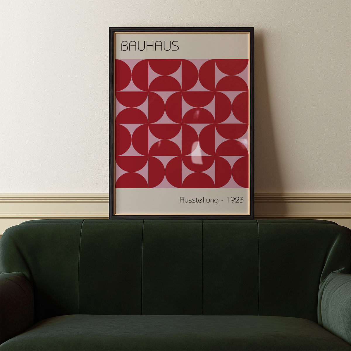 Framed Bauhaus artworks with red geometric pattern above a dark green sofa