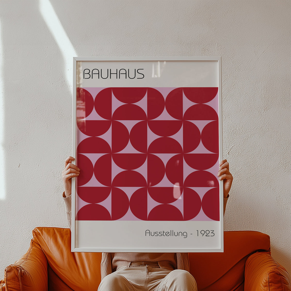 Framed Bauhaus Artworks print with a red geometric pattern held by a person on an orange sofa