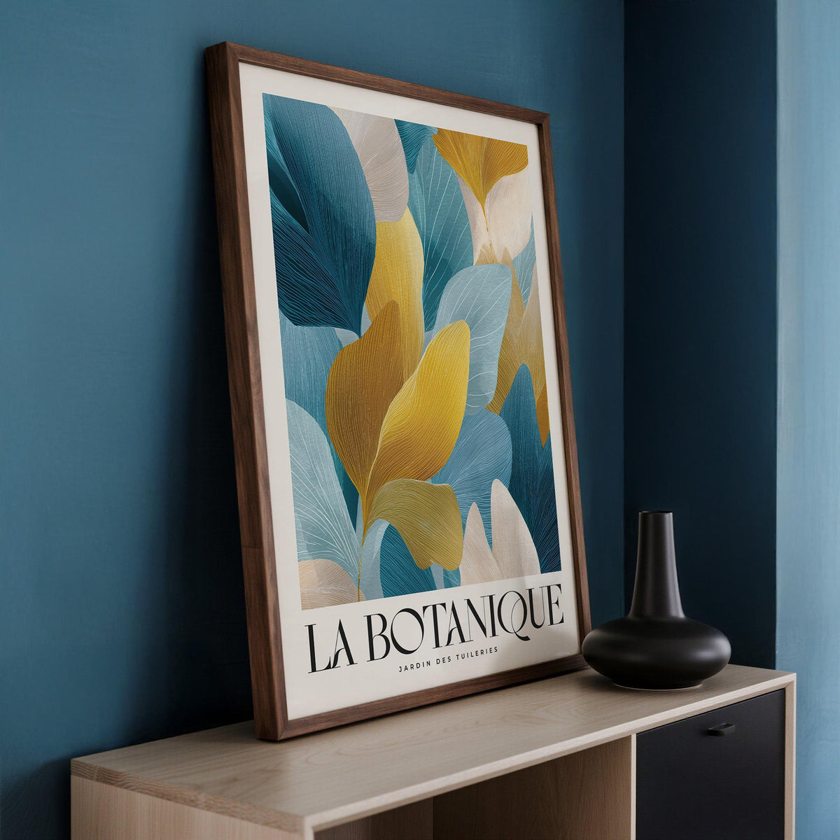 Framed print close-up of blue and gold leaves with botanical text on a sideboard with a dark vase